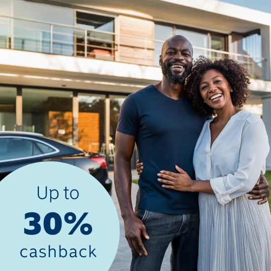 Comedian Tyson Ngubeni smiling in a house and displaying the Momentum App on this phone with a 30% cash back on car and home insurance premiums when joining Safety Returns.