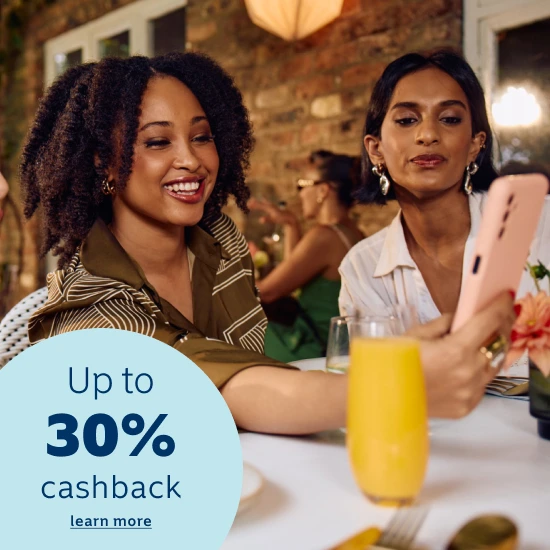 Comedian Tyson Ngubeni smiling in a house and displaying the Momentum App on this phone with a 30% cash back on car and home insurance premiums when joining Safety Returns.