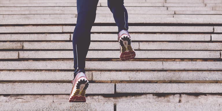 Close up of legs wearing tights and training shoes, running up a flight of stairs.