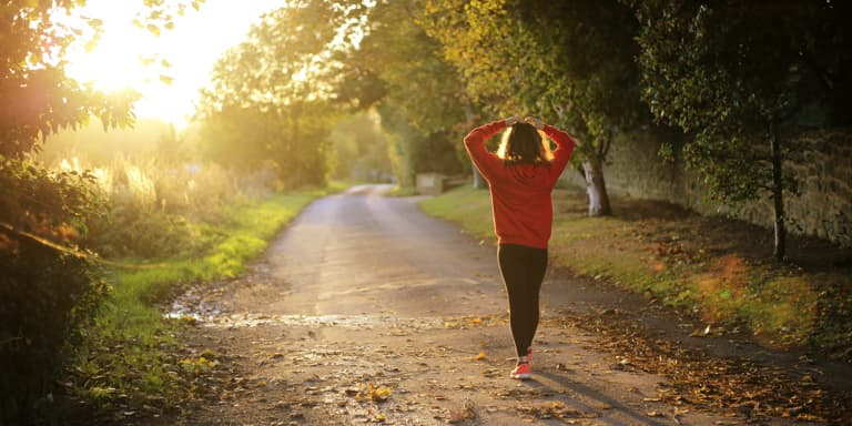 A lady wearing sporty clothes, stretching in front of an open road in the crack of dawn before her jog.