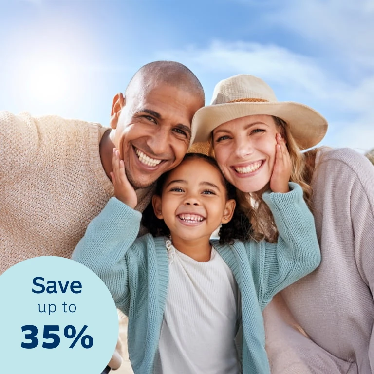 Parents enjoy a day outdoors with their young daughter. The daughter is standing in the middle of them with her hands on each parent's cheeks.