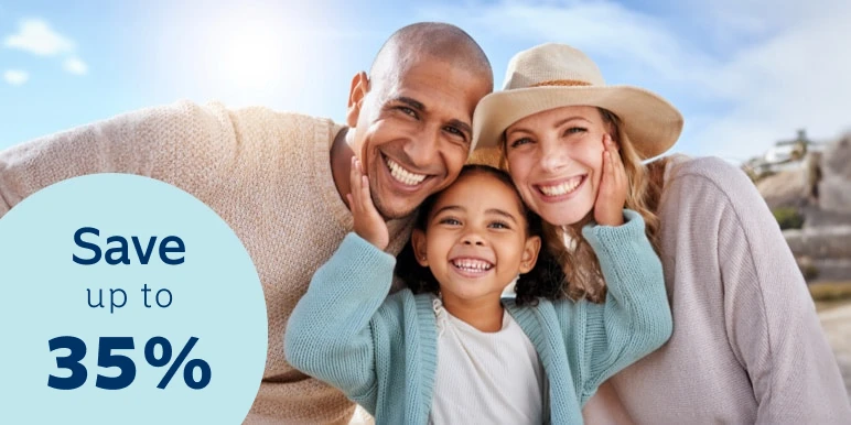 Parents enjoy a day outdoors with their young daughter. The daughter is standing in the middle of them with her hands on each parent's cheeks.