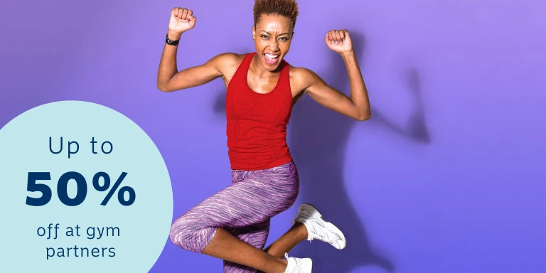 An athletic lady in a red sleeveless top and purple training pants jumping up as she reached her fitness goals with Momentum Multiply.