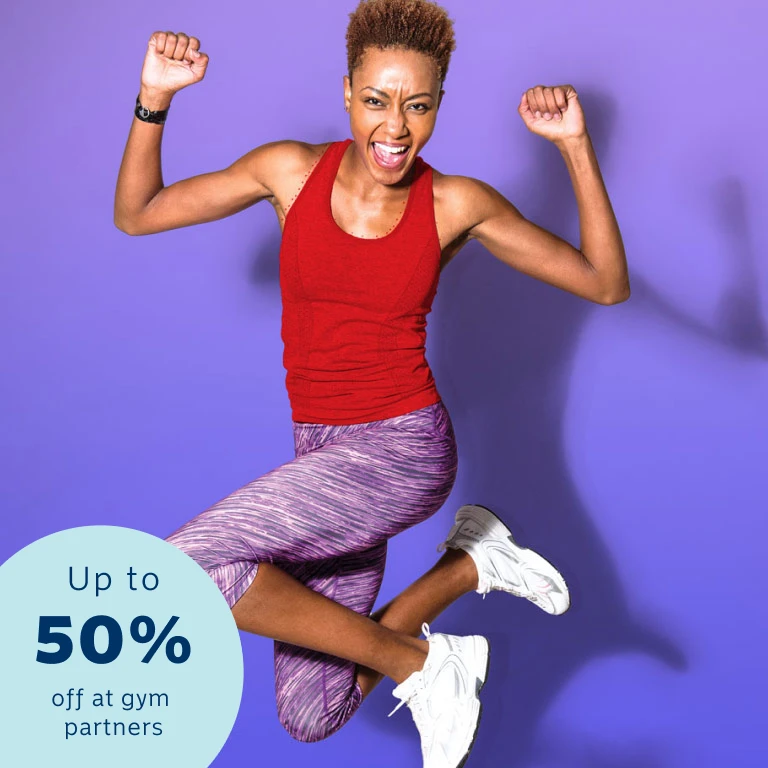 An athletic lady in a red sleeveless top and purple training pants jumping up as she reached her fitness goals with Momentum Multiply.