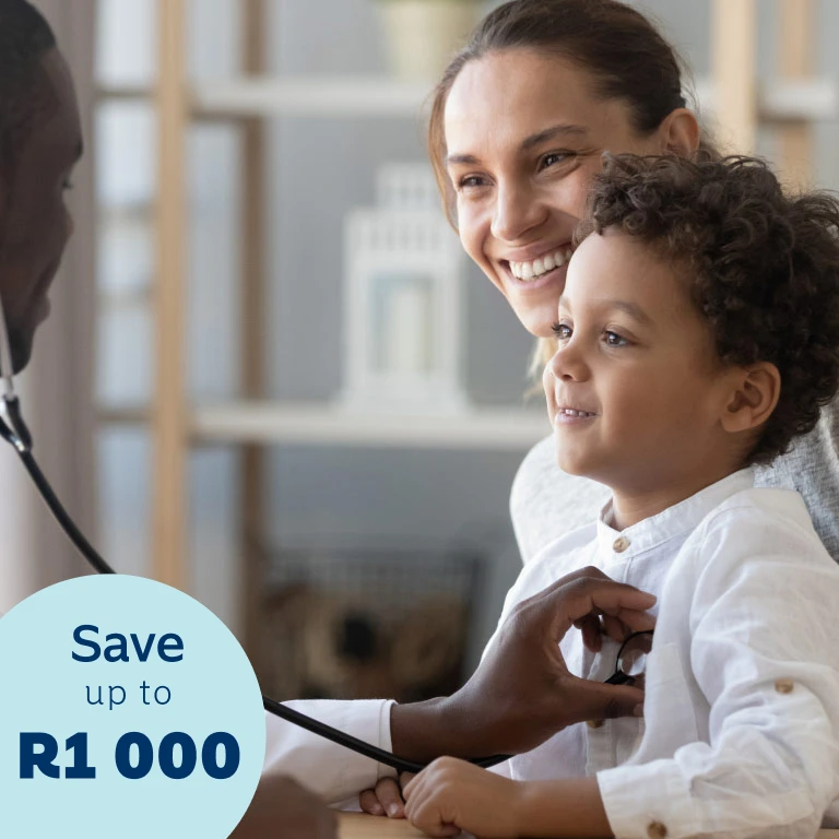 A content little boy sitting on his mother’s lap gets his chest examined by a young male doctor using a stethoscope.