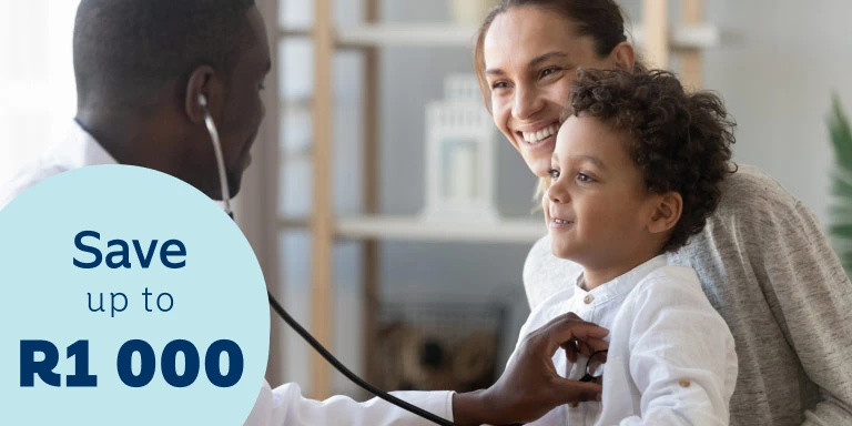 A content little boy sitting on his mother’s lap gets his chest examined by a young male doctor using a stethoscope.