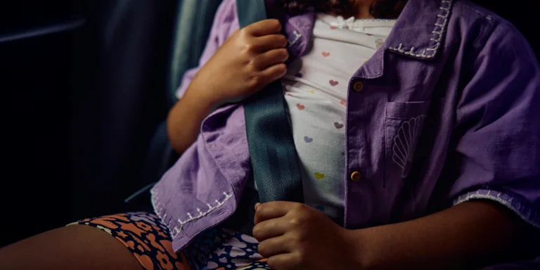 A young passenger buckled securely in the backseat of a car, emphasizing road safety and family protection.