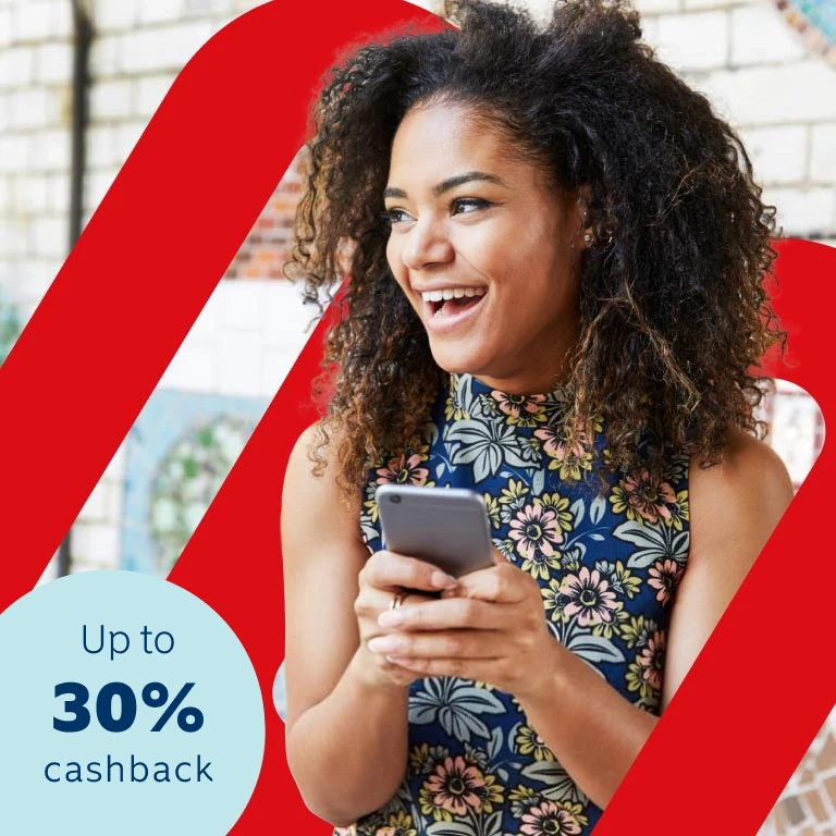 Young lady with a blue floral top holding a cell phone in her hands smiling as she discovered she can earn up to 30% of paid premiums back in cash every year, even if you claim, at no additional cost.