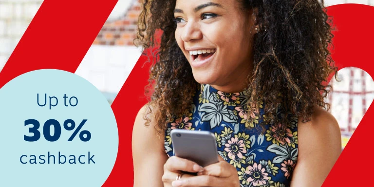 Young lady with a blue floral top holding a cell phone in her hands smiling as she discovered she can earn up to 30% of paid premiums back in cash every year, even if you claim, at no additional cost.