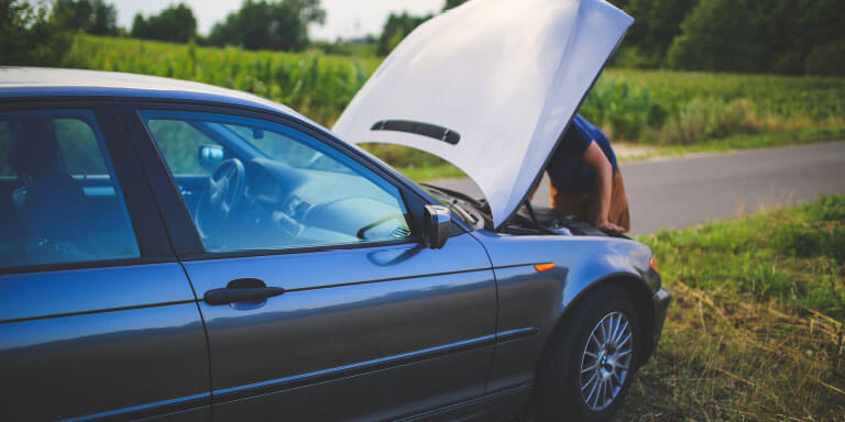 A man looking under the hood of his car.