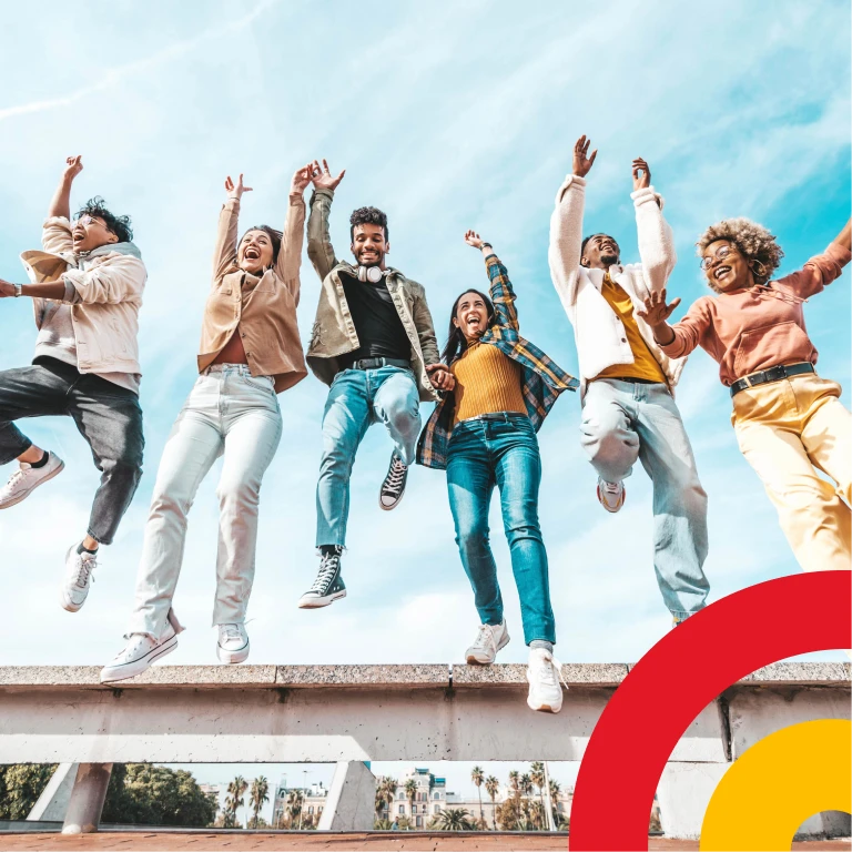 A happy young African woman wearing a vibrant headscarf smiles as she looks at her cell phone.
