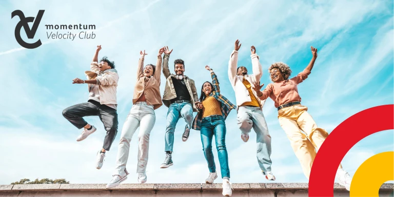 A happy young African woman wearing a vibrant headscarf smiles as she looks at her cell phone.
